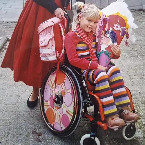 Mädchen im Rollstuhl mit Schultüte bei der Einschulung.