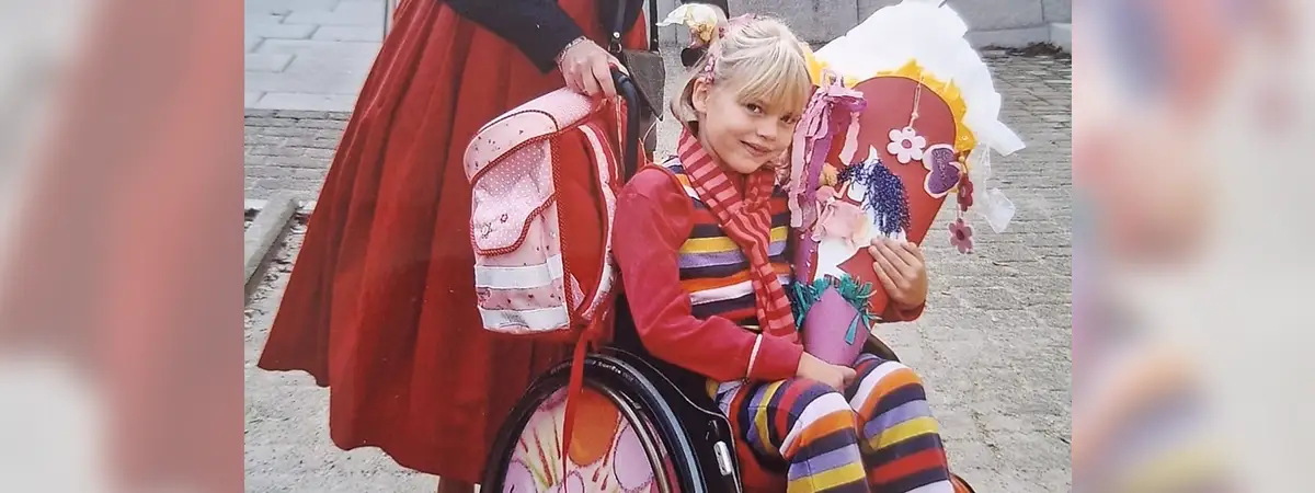 Mädchen im Rollstuhl mit Schultüte bei der Einschulung.