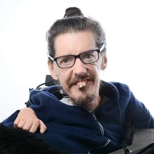 Christian sitzt im Elektrorollstuhl und blickt freundlich in die Kamera.