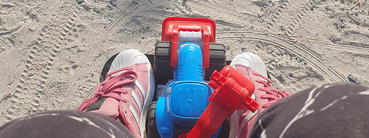 Alina fährt im Elektrorollstuhl, zwischen ihren Füßen liegt Sandspielzeug.