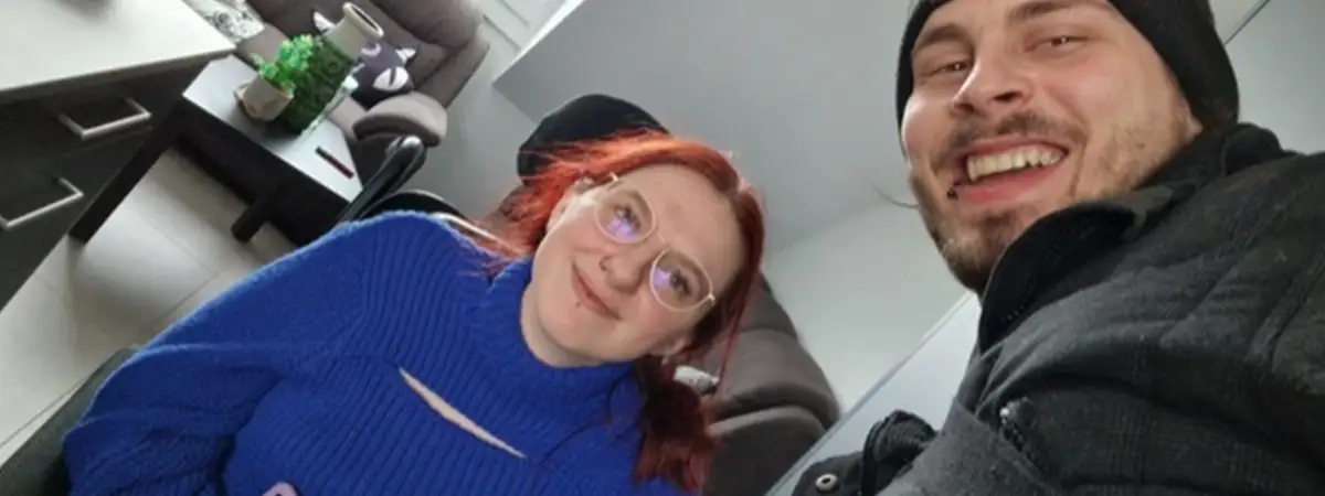 Lys und ihr Ehemann stehen in einer Wohnung und blicken freundlich in die Kamera