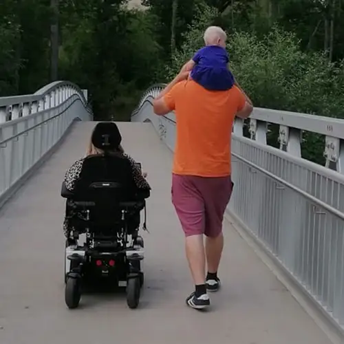Sandra und ihre Familie gehen über eine Brücke, Sicht von hinten
