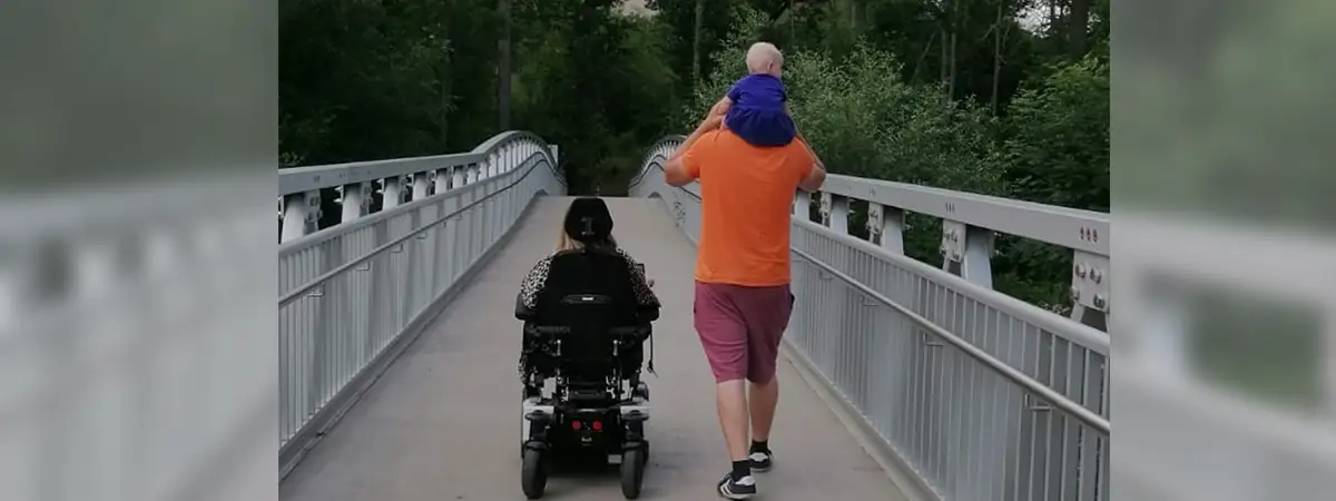 Sandra und ihre Familie gehen über eine Brücke, Sicht von hinten
