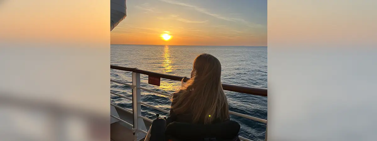 Ein Foto von Lilli, während sie zum Sonnenuntergang und zum Meer schaut.