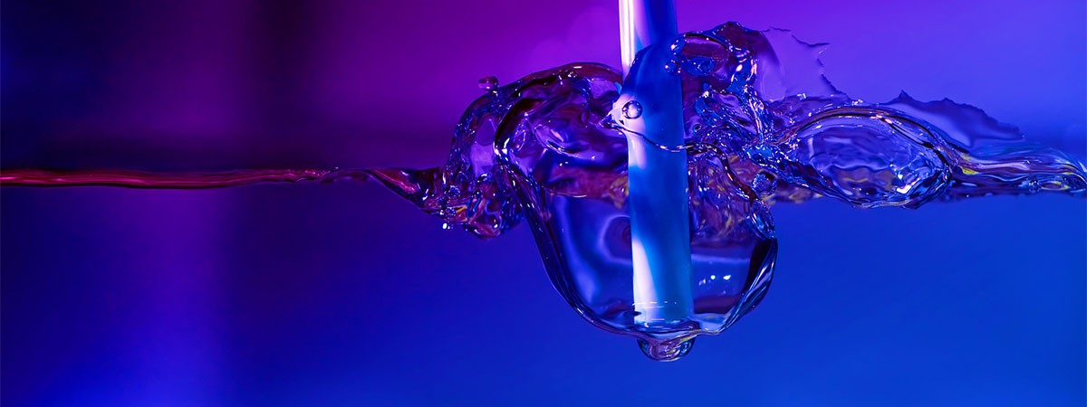 Ein lila eingefärbtes Bild, auf dem Ein Strohhalm zu sehen ist, der in eine Flüssigkeit getunkt wird.