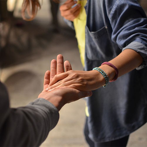 Zwei Menschen geben sich gegenseitig helfend die Hand.