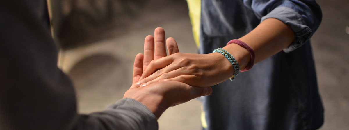 Zwei Menschen geben sich gegenseitig helfend die Hand.