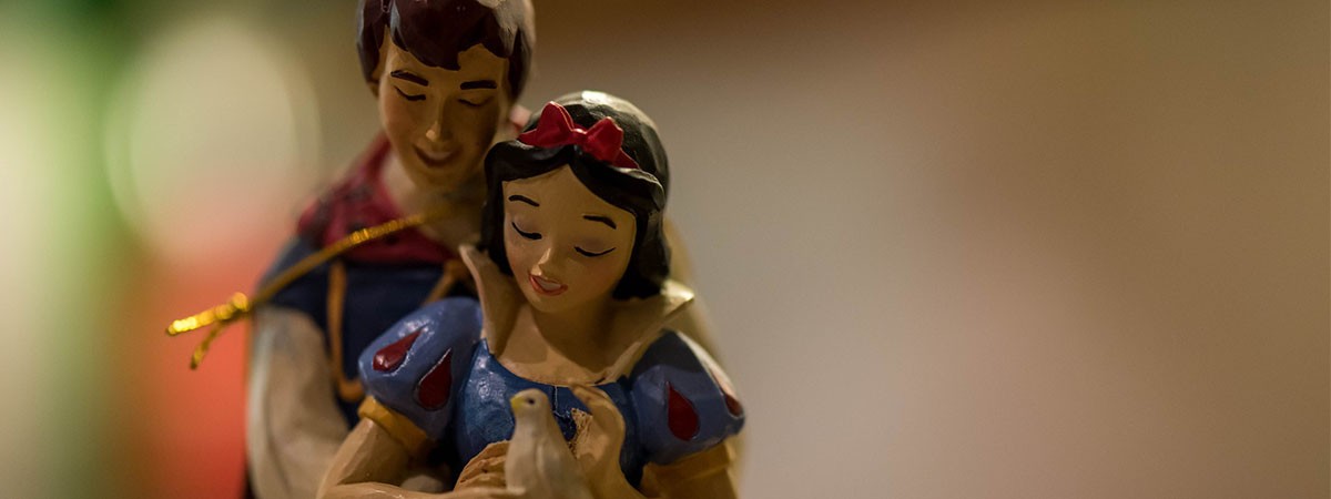 Zwei Holzfiguren sind zu sehen: Schneewittchen und ihr Märchenprinz, der sie umarmt.