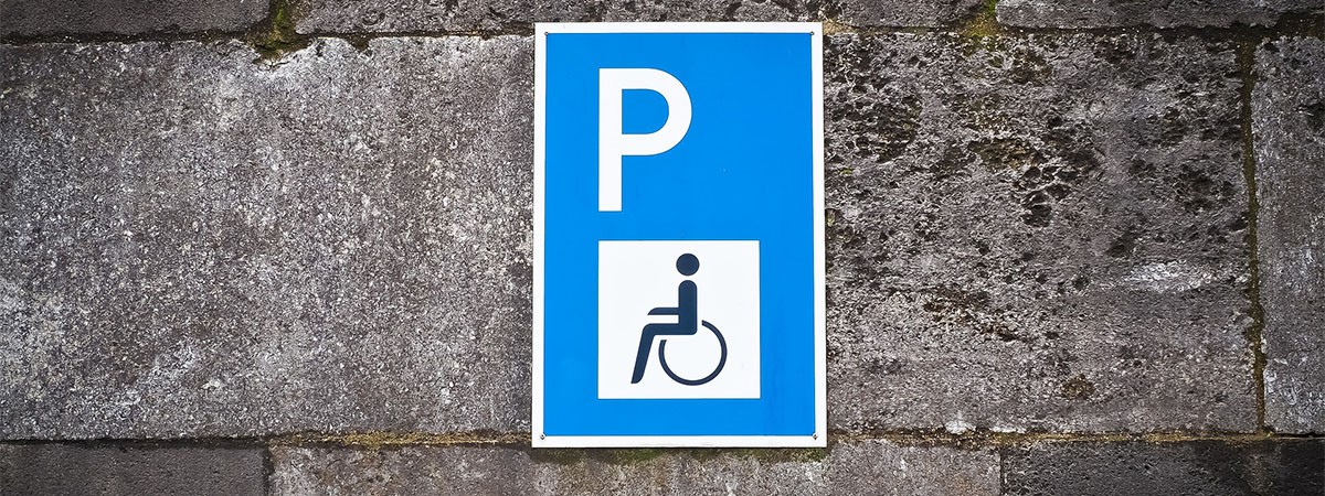 Ein Straßenschild mit einem Rollstuhlsymbol, das einen Parkplatz als Behindertenparkplatz kennzeichnet.