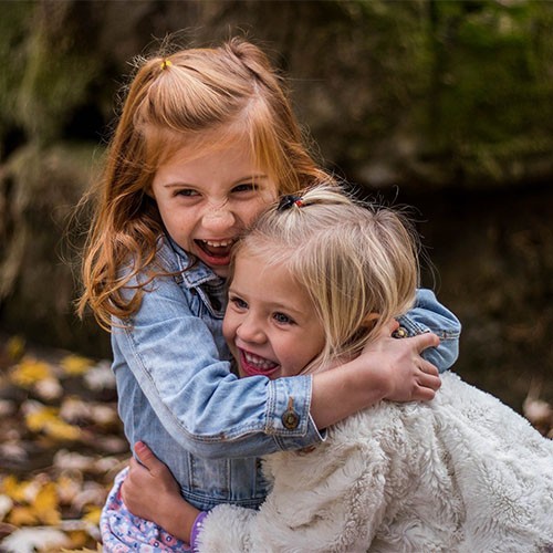 Zwei Mädchen umarmen sich. Die beiden Freunde sind glücklich und lachen.